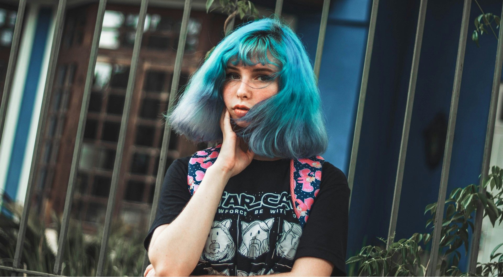 Young girl with blue hair standing outside a bank